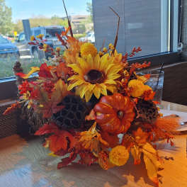 Autumn floral centerpiece with sunflowers, pumpkins, and fall leaves