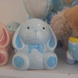 Blue ceramic bunny figurine with a bow sits on a shelf