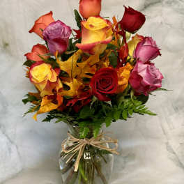 Mixed roses in a glass vase with autumn leaves