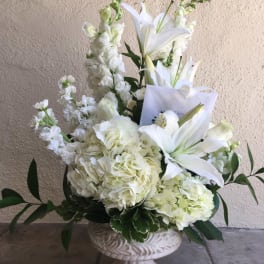 White lilies and hydrangeas in a pedestal vase