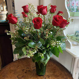 Red roses arranged in a clear glass vase with white filler flowers