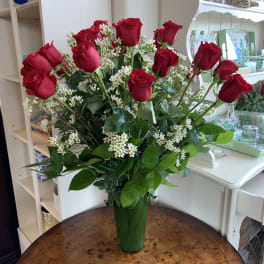 Bouquet of red roses and white filler flowers in a green glass vase