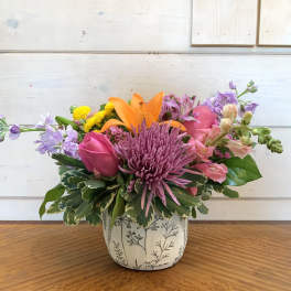Mixed bouquet in a patterned ceramic pot with pink, purple, and orange blooms