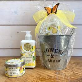 Gift basket with a metal flower bucket, lotion, and candle tied with a yellow bow