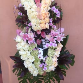 Standing floral funeral spray with white and pink roses, orchids, and lilies