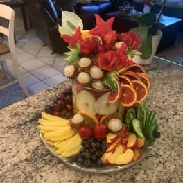 Tiered fruit platter with carved fruit flowers and sliced citrus on a tray