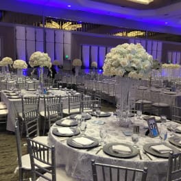 White floral centerpieces on round banquet tables in a reception hall