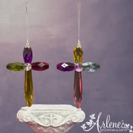 Two colorful crystal cross ornaments hang above a carved pedestal