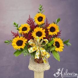Sunflower arrangement in a decorative vase with a sunflower ribbon