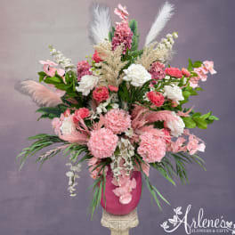 Pink and white floral arrangement in a magenta vase with feathery accents