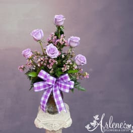 Lavender roses in a glass vase with a purple checkered bow