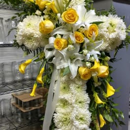 Large yellow and white floral standing spray with roses, lilies, and chrysanthemums