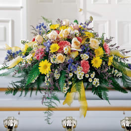 Colorful floral casket spray with roses, daisies, and ribbons