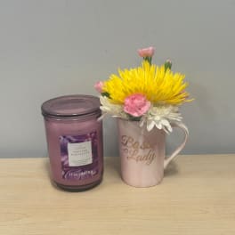 Pink and yellow flowers in a mug beside a purple candle jar.