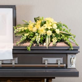Yellow floral spray on top of a casket