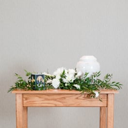 White floral funeral arrangement with an urn and memorial candle