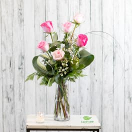 Pink roses in a clear glass vase with a small candle beside it