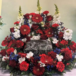Large red, white, and blue floral arrangement around a marble urn