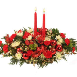 Red and white floral centerpiece with two red taper candles and shiny red ornaments.