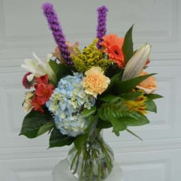 Mixed bouquet in a clear glass vase with hydrangea, lilies, and gerbera daisies