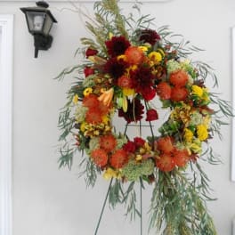 Large floral wreath on a stand with red, orange, and yellow blooms