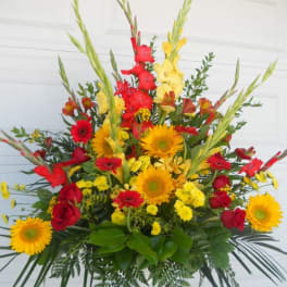 Large arrangement of red and yellow flowers in a white container
