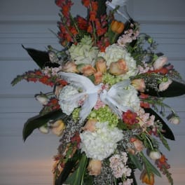 Large standing floral spray with white doves and peach, white, and orange flowers