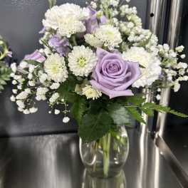 Lavender roses and white flowers in a clear glass vase