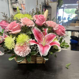 Pink roses and lilies arranged in a wicker basket