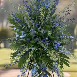 Tall blue floral spray on a stand with mixed greenery