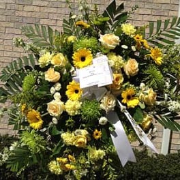 Large yellow and white funeral spray with ribbon on an easel