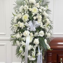 White funeral spray with roses and chrysanthemums on an easel