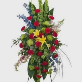 Tall standing floral spray with red, yellow, blue, and green flowers