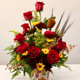 Red roses and yellow chrysanthemums in a vase with fall accents
