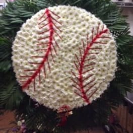 White floral funeral wreath with red accents and dark greenery