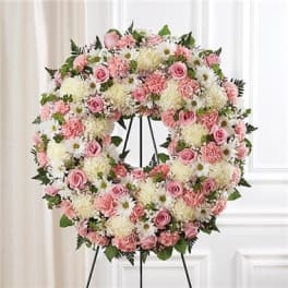 Pink and white floral wreath on a black stand