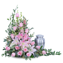 Pink roses and lilies arranged beside a silver urn