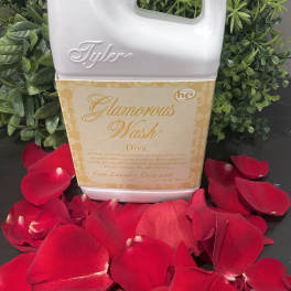 Laundry detergent bottle surrounded by red rose petals and greenery
