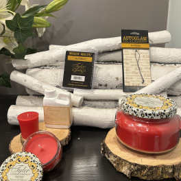 Assorted red candles and Tyler fragrance products on wood slices