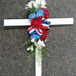 Floral cross with red, white, and blue flowers and ribbon
