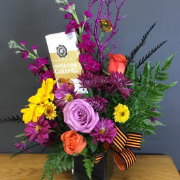 Mixed bouquet with roses, chrysanthemums, and a chocolate bar in a black vase