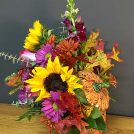 Autumn bouquet with sunflowers, purple daisies, and a decorative pumpkin