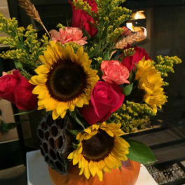 Bouquet with sunflowers, red roses, and pink carnations in a vase