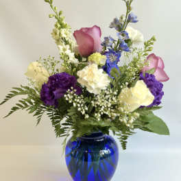 Mixed bouquet in a blue glass vase with pink, purple, white, and yellow flowers