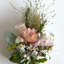 Pink and white floral arrangement with a large central bloom and airy grasses