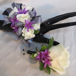 Two white rose boutonnieres with purple accents and silver ribbon