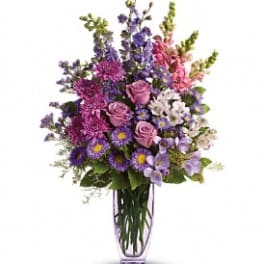 Purple and pink mixed flower arrangement in a clear glass vase