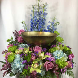Colorful floral arrangement with a gold bowl centerpiece and tall blue flowers