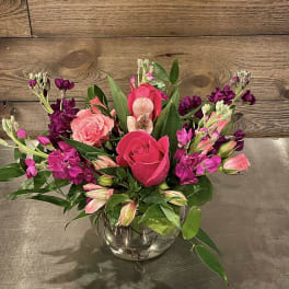 Pink and purple floral arrangement in a clear glass bowl vase