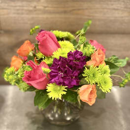 Colorful mixed bouquet in a glass vase with roses and mums